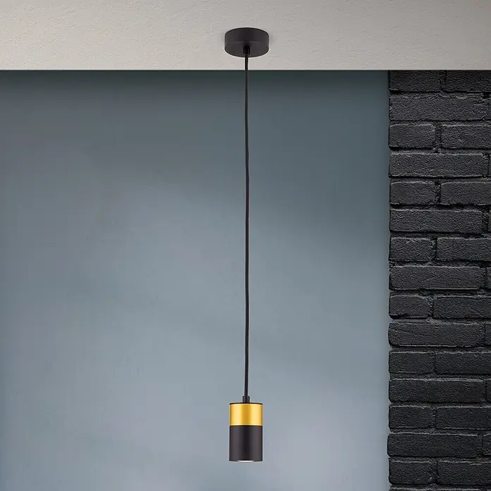 Orion Leuchten Pendelleuchte Martini H 9.5 cm -  - Zylindrische Pendelleuchte in Schwarz-Gold mit Kabel, vor einer grau-blauen Wand und schwarzem Backstein.