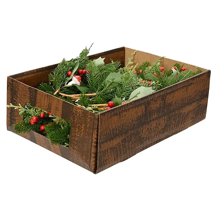 Rama artificial de pino decorado - 20 cm, Plástico - Caja marrón con ramas verdes de abeto, bayas rojas y decoraciones navideñas.