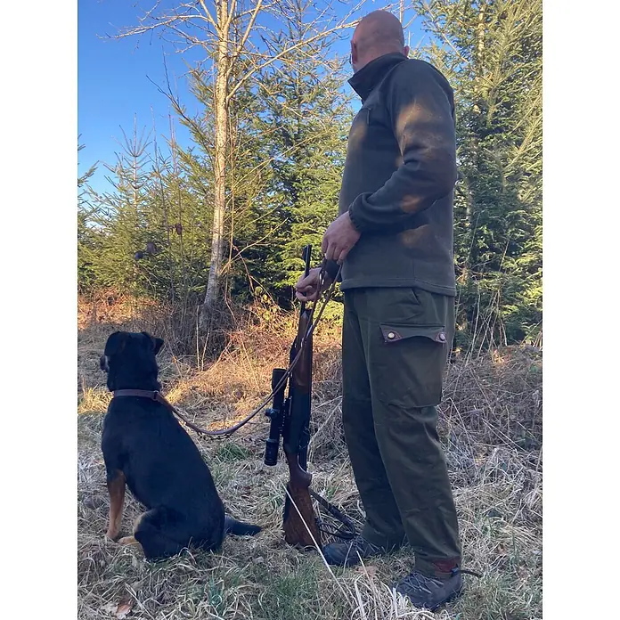 Hundeleine / Führleine - Echtleder mit Halsband – handgefertigt in Germany -  - Mann in grüner Outdoor-Fleecejacke, Hose und Stiefeln mit Gewehr und Hund im Wald.