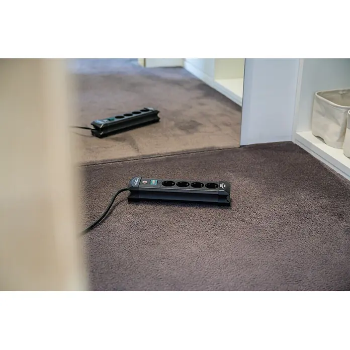 Brennenstuhl Premium-Line Steckdosenleiste - Schwarz, Kabellänge: 1,8 m, Mit Schalter - Schwarze Kunststoff-Steckdosenleiste mit fünf Anschlüssen und Schalter, auf einem dunkelgrauen Teppich.