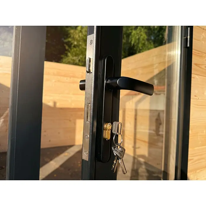 Fjordholz 2-Raum Gartenhaus  Alu Line 44-F, 19.20  m², Isoliervergl. -  - Schwarzer Türgriff mit Schloss, Messingzylinder und silbernen Schlüsseln, in einer dunkel gerahmten Glastür installiert.