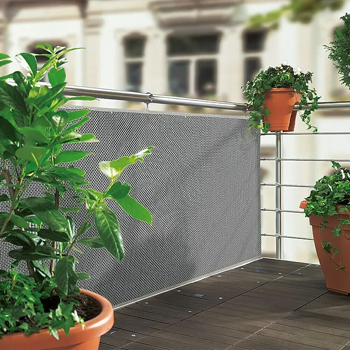 Sunfun Balkonsichtschutz - Grau, 300 x 90 cm - Balkon mit einem Sichtschutz aus grauem Netzgewebe, umgeben von üppigen Grünpflanzen in Terrakottatöpfen.