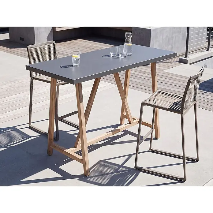 Esstisch TALAMONE in Braun/Grau - (W) 70 x (H) 100 x - L - Ein Outdoor-Bartisch mit dunkelgrauer Platte und Holzbeinen, dazu zwei Barhocker mit Metallrahmen und geflochtenen Sitzen, auf einer Terrasse.