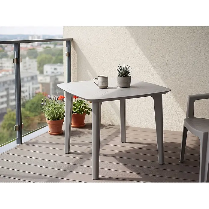 Esstisch SORICO in Grau - (W) 86 x (H) 77 x - L - Grauer quadratischer Gartentisch auf einem Balkon mit Tasse und Pflanze.
