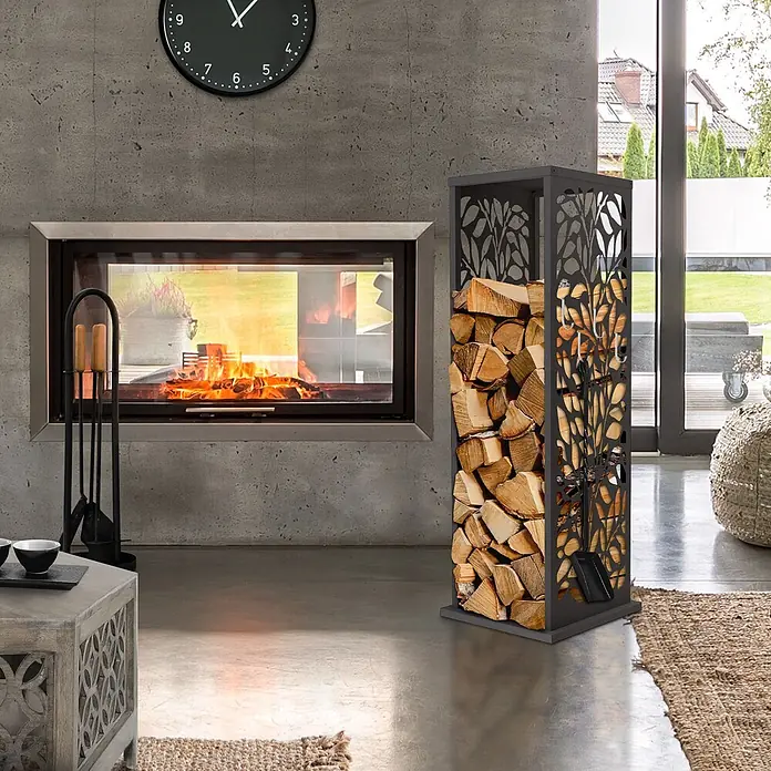 ML-Design Kaminholzregal Metall 37,5x37,5x112 cm Anthrazit Blätter-Motiv -  - Dunkles Metall-Holzregal mit Zier-Blattmuster, gefüllt mit Holzscheiten, steht neben einem modernen Kamin mit Kaminbesteck.