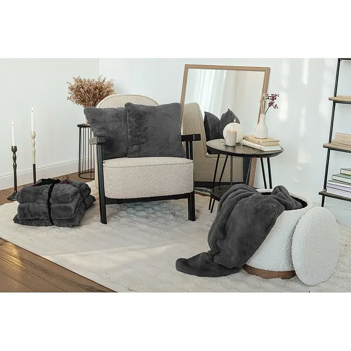 Dekokissen & Decken-Set Aimee - 2 -tlg., Anthrazit - Gemütliches Wohnzimmer mit weichen grauen Kunstpelzdecken und Kissen, auf einem Sessel und in einem Aufbewahrungskorb platziert.