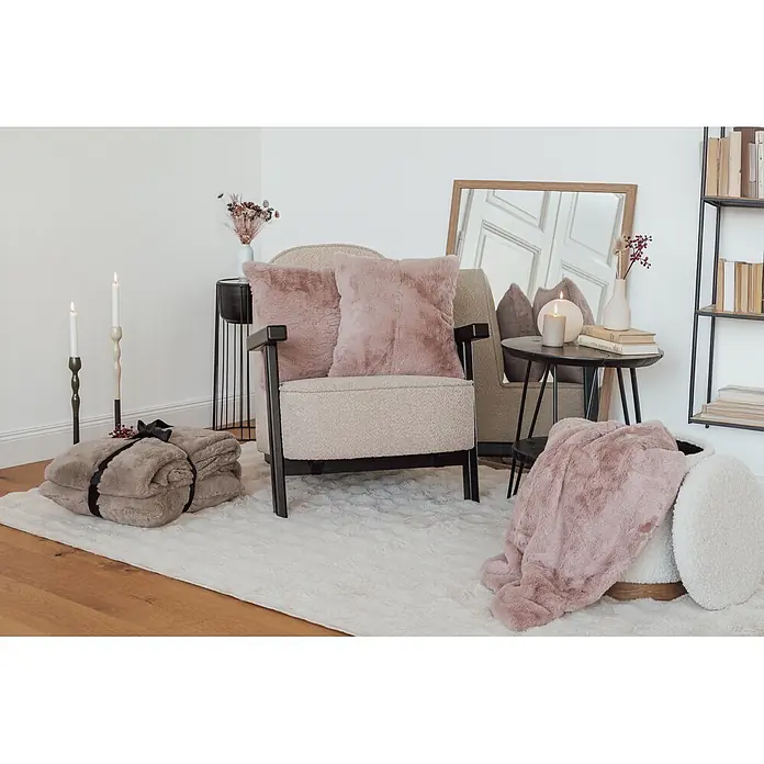 Dekokissen & Decken-Set Aimee - 2 -tlg., Rosa - Gemütliches Wohnzimmer mit beigem Sessel, rosa flauschigen Kissen und Decken. Ein weißer Flausch-Teppich bedeckt den Holzboden.