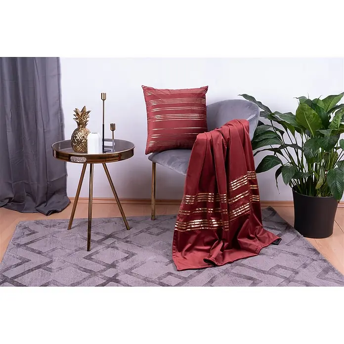 Dekokissen & Decken-Set Prisma - 2 -tlg., Rot/Gold - Rotes Samtkissen und passende Decke mit eleganten goldenen Querstreifen, auf einem grauen Sessel drapiert.
