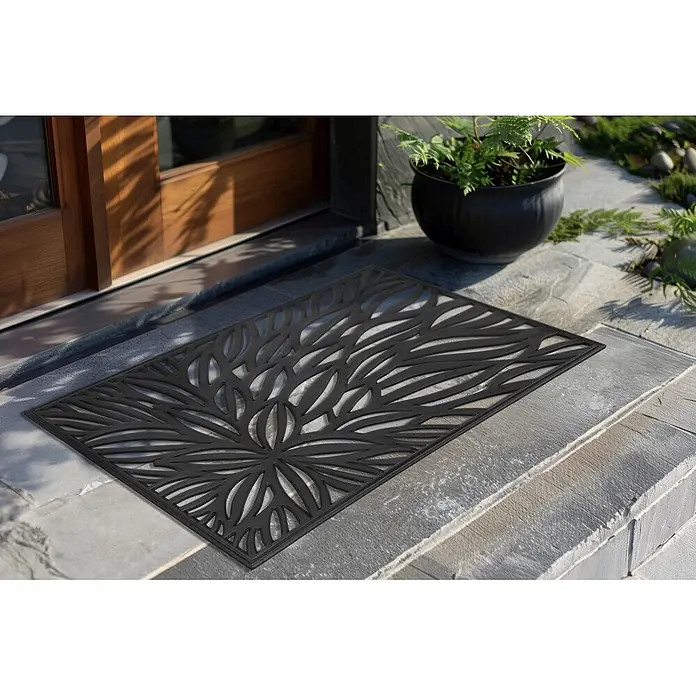 Fußmatte Everyday 225 - 75 x 45 cm, Schwarz, Material Nutzschicht: 100 % Gummi - Schwarze Fußmatte mit dekorativem Blättermuster-Ausschnitt, auf einer Steintreppe vor einer Holztür platziert.