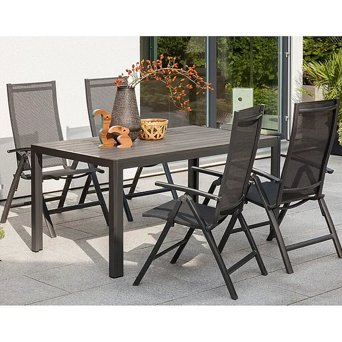 Sunfun Maja Sillón de posiciones - 61 x 68 x 110 cm, Antracita, Aluminio/Textiline - Un conjunto de comedor exterior con una mesa y cuatro sillas, situado en un patio. El mobiliario tiene un diseño oscuro y moderno.