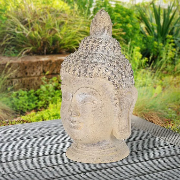 Buddha Kopf 30 x 30 x 55 cm, Beige-Grau -  - Hellfarbene, verwitterte Buddha-Kopf-Statue für Garten- oder Außendekoration, auf einer Holzterrasse.