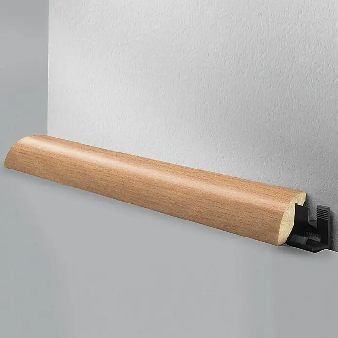 LOGOCLIC Viertelstab Buche - 260 cm x 23 mm x 29 mm, MDF - Eine Viertelstab-Fußleiste aus Holz mit einem Befestigungsclip aus Kunststoff, montiert an einer Wand, dient als dekoratives Element.