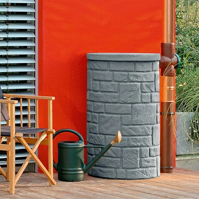 Arves Regenspeicher Arcado - 230 l, Black Granitfarben - Grauer Regentonne in Steinoptik mit einer grünen Gießkanne daneben, die sich perfekt für die Gartenbewässerung eignet.