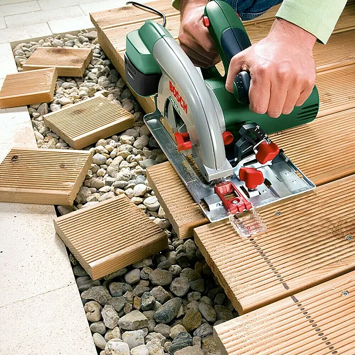 Bosch Handkreissäge PKS 55 A - 1.200 W, 5.600 U/min - Die Bosch Handkreissäge beim Zuschneiden von Holz auf einer Baustelle, ideal für präzise Holzarbeiten im Garten und Haus.