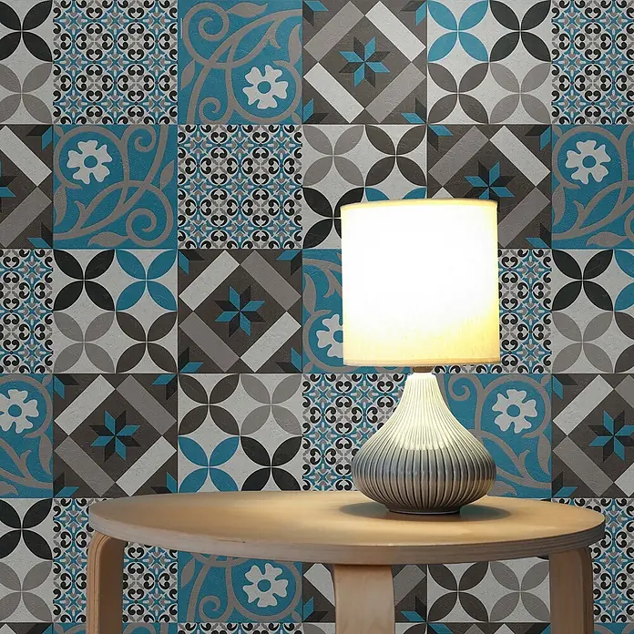 Tapete Fliesen Luca M1-No.522 Vliestapete Schwarz Blau Landhaus -  - Eine moderne Tischlampe mit geripptem grauem Fuß und leuchtendem Schirm steht auf einem runden Holztisch vor einer gemusterten blau-grauen Fliesenwand.