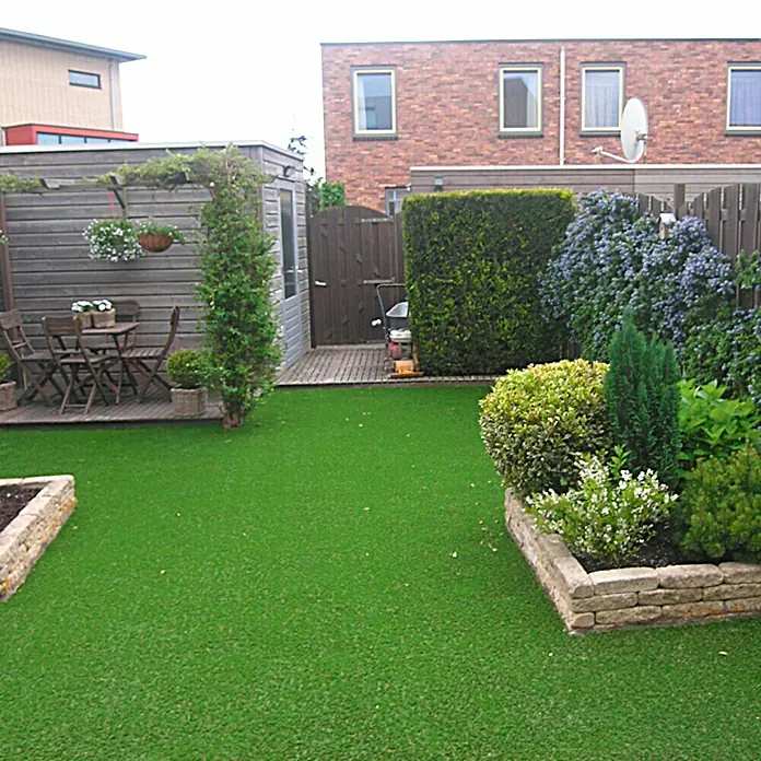 Rasenteppich Meterware Green - Breite: 150 cm, Grün, Mit Drainagenoppen - Gepflegter Garten mit Kunstrasen, Steinbeeten und Holzsitzgruppe. Ein idyllischer Außenbereich für Entspannung und Genuss.