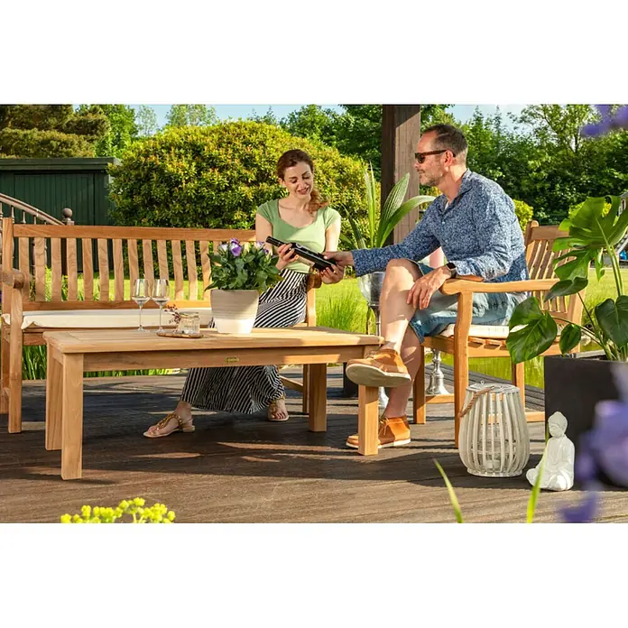 Teak Loungetisch Massivholz 120 x 60 cm wetterfest pflegeleicht und edel -  - Gartenmöbel-Set aus Teakholz mit Bank, Tisch und Stuhl, von zwei Personen im Garten genossen.