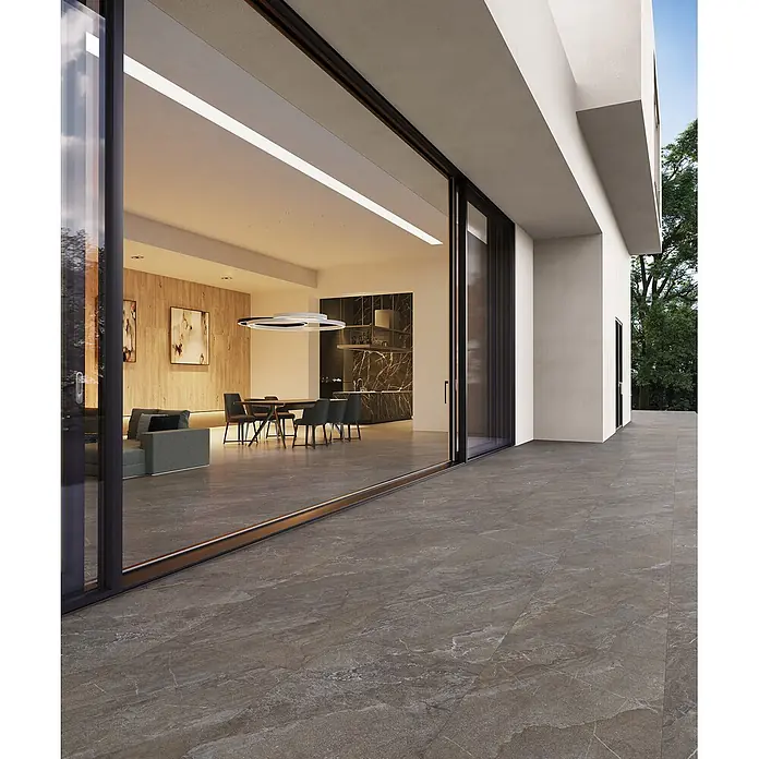 Feinsteinzeug in brauner Steinoptik 60x120, 20 mm, rutschhemmend -  - Großformatige, braun-grau marmorierte Outdoor-Fliesen auf einer modernen Terrasse, die sich von einem Haus mit Glasschiebetüren erstreckt.