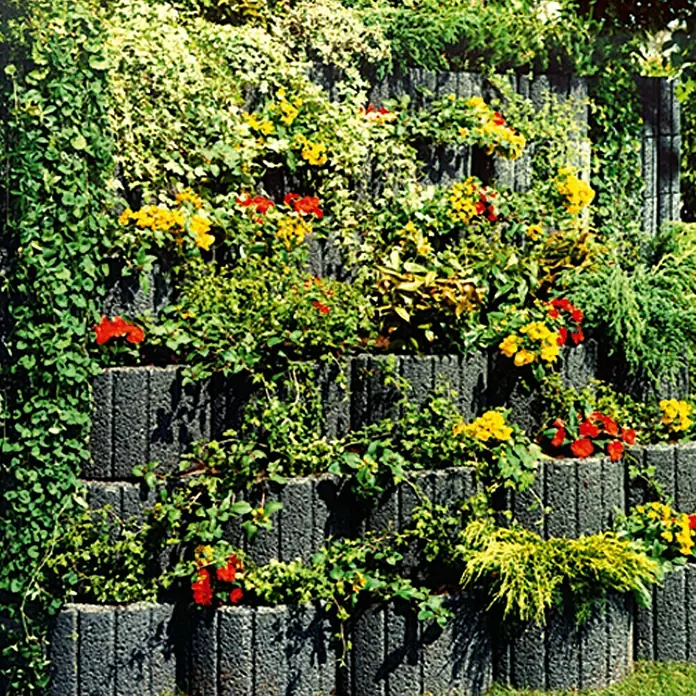 EHL Pflanzstein Stützflor - Anthrazit, 50 x 40 x 30 cm, Beton - Gestufte Gartenmauer aus grauen Betonsteinen, bepflanzt mit üppigen Blumen und Kletterpflanzen für einen lebendigen Farbakzent.