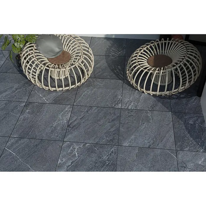 Feinsteinzeug in Jerusalem anthrazit Steinoptik 60x60 - Ital. Fliesen -  - Dunkelgraue Außenfliesen mit heller Äderung bedecken einen Terrassenboden, zusammen mit zwei Rattanstühlen.