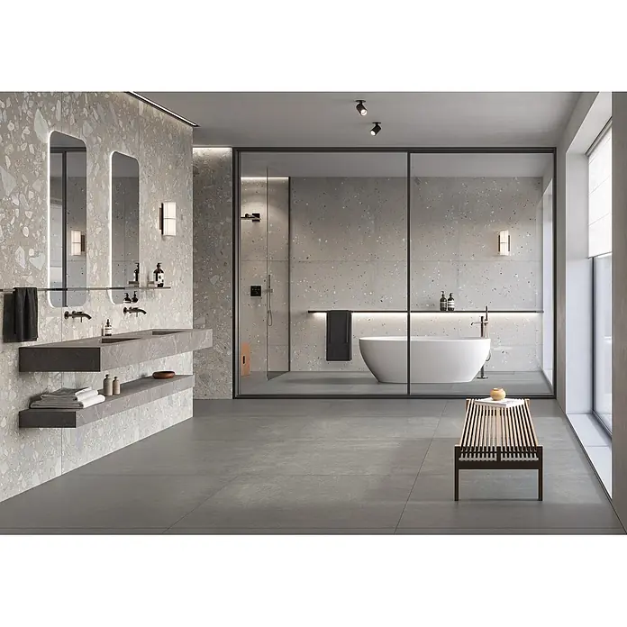 Feinsteinzeug in Pure schwarzer Steinoptik 60x60 - Italienische Fliesen -  - Modernes Badezimmer mit hellen Terrazzo-Wänden, dunkelgrauen Bodenfliesen und schwebendem Doppelwaschtisch. Glasabtrennung für Dusche und freistehende Badewanne.