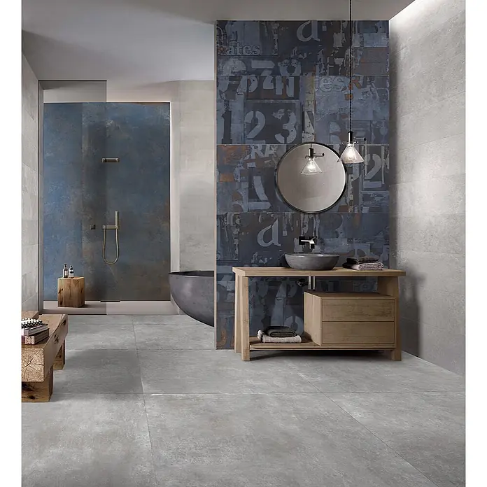 Dekorierte industrielle Feinsteinzeug Wandfliese in Blau - Ital. Fliesen -  - Modernes Badezimmer mit hellgrauen Boden- und Wandfliesen, akzentuiert durch eine Wand mit blauen Rost-Grafikfliesen mit Zahlen und Buchstaben.