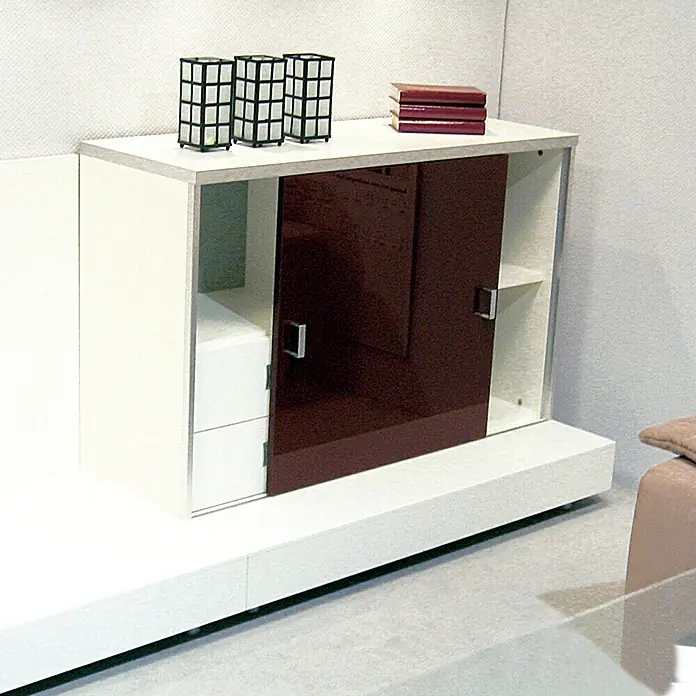 HBS Betz Gleittürbeschlag - Traglast: 6 kg, Länge: 150 cm, Einsatzbereich: Schrankschiebetüren - Weißer Schrank mit burgunderroten Schiebetüren, verziert mit Dekorationsgegenständen und Büchern auf der Oberseite.