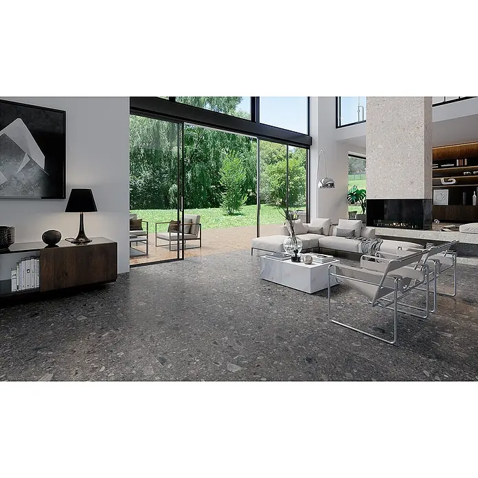 Feinsteinzeug in matter anthrazitfarbener Steinoptik 30x60 - Ital. Fliesen -  - Dunkelgraue, gesprenkelte Bodenfliesen in einem modernen Wohnzimmer, das sich zu einem Garten öffnet und Innen- und Außenbereiche verbindet.