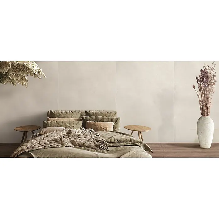Feinsteinzeug in farbiger weißer Betonoptik 60x60 - Italienische Fliesen -  - Helle beigefarbene Wandfliesen schaffen eine ruhige Schlafzimmeratmosphäre, ergänzt durch neutrale Bettwäsche und Holzdetails.