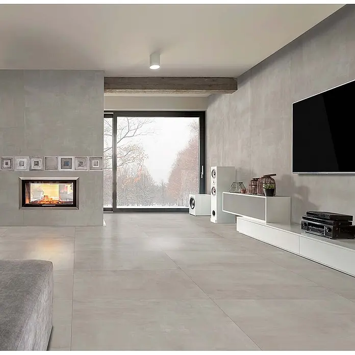Feinsteinzeug in gebürsteter perlgrauer Betonoptik 60x60 - Ital. Fliesen -  - Große graue Fliesen bedecken den Boden eines modernen Wohnzimmers mit Kamin und TV-Bereich.