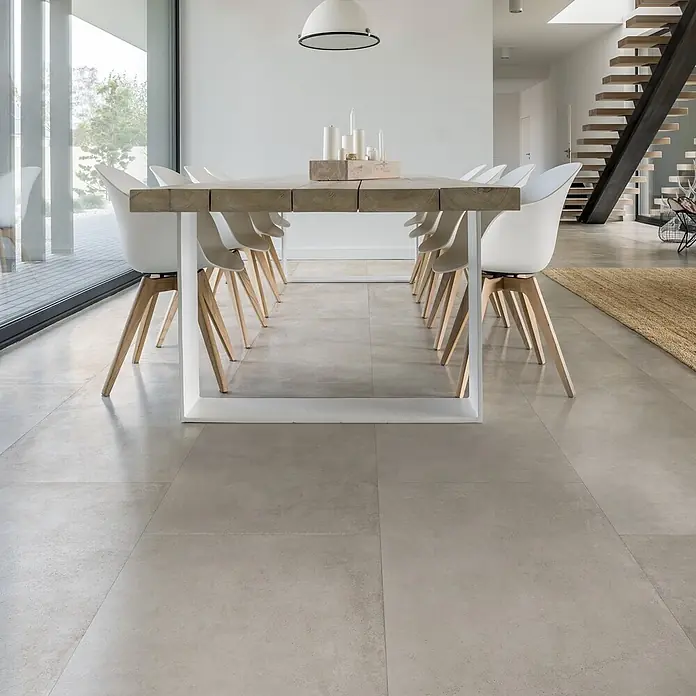Feinsteinzeug in gewachster weißer Betonoptik 120x120 - Ital. Fliesen -  - Modernes Esszimmer mit hellgrauen Bodenfliesen, einem Holztisch und weißen Stühlen.