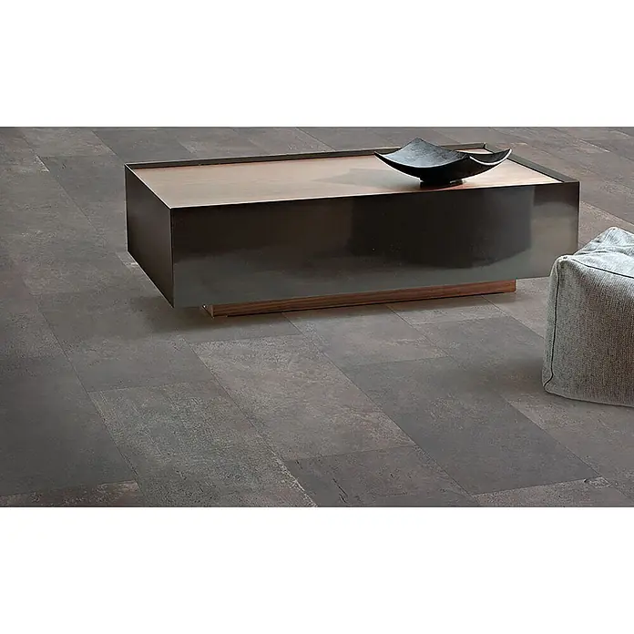 Feinsteinzeug in metallischer brauner Betonoptik 60x120 - Ital. Fliesen -  - Dunkelgraue, rechteckige Bodenfliesen mit strukturierter Oberfläche, unter einem Couchtisch und neben einem grauen Pouf verlegt.