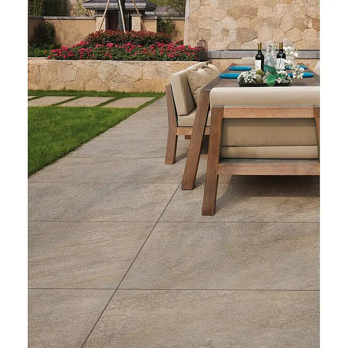 Feinsteinzeug in beiger Steinoptik 60x60, 20 mm, rutschhemmend -  - Strukturierte beigefarbene Terrassenplatten bilden eine moderne Terrasse, neben Rasen mit Trittsteinen und einem Essbereich im Freien.