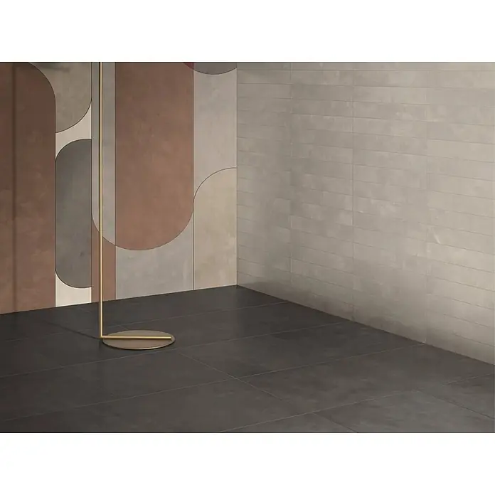 Feinsteinzeug-Fliesen in schwarzer Beton-Harz-Optik 60x120 - Ital. Fliesen -  - Moderne Raumecke mit dunkelgrauen Bodenfliesen, abstrakt gemusterten Wandfliesen, hellgrauen Rechteck-Wandfliesen und einem goldenen Bodenständer.