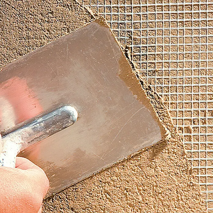 Catnic Innenputzgewebe - 50 x 1 m - Nahaufnahme eines Werkzeugs beim Auftragen von Putz auf ein Gitter, das für die Bauindustrie verwendet wird.