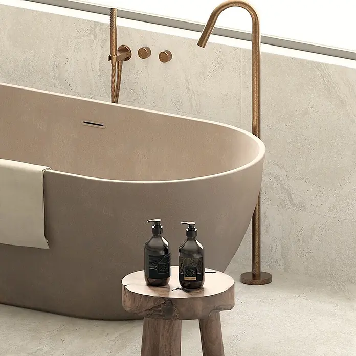 Design-Feinsteinzeug Weiß matt 120x120 - Italienische Fliesen -  - Eine hellbraune, freistehende Badewanne in einem modernen Badezimmer mit messingfarbenen Armaturen und einem Holzhocker mit dunklen Pumpspendern.