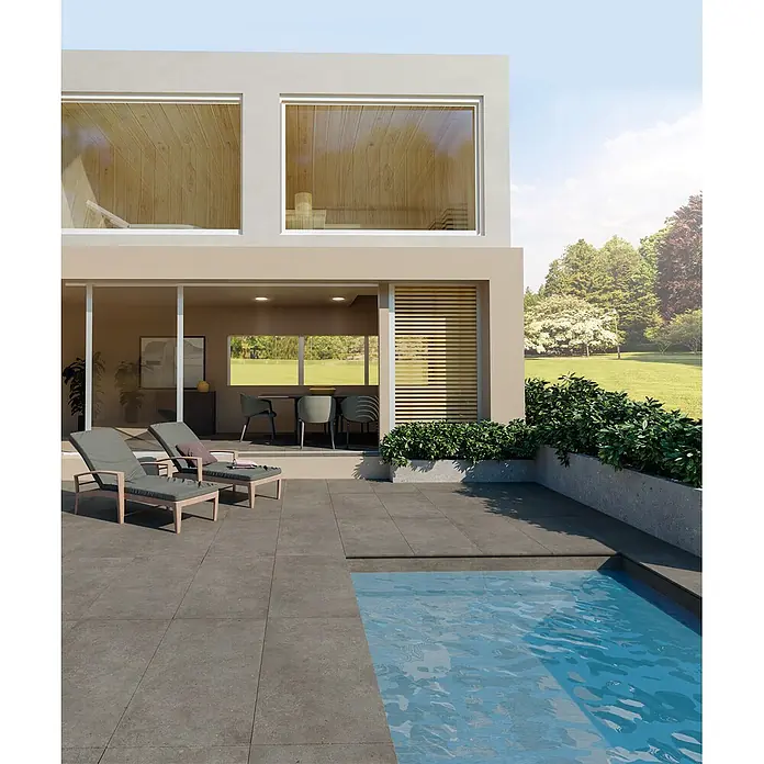 Feinsteinzeug in grauer aschgrauer Betonoptik 60x60 - Italienische Fliesen -  - Dunkelgraue Outdoor-Terrassenfliesen umgeben einen Pool und ein modernes Haus, bieten eine langlebige und zeitgemäße Oberfläche.