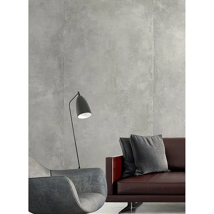 Feinsteinzeug in gewachster hellgrauer Betonoptik 60x120 - Ital. Fliesen -  - Graue strukturierte Wandpaneele in einem modernen Wohnzimmer mit Ledersofa und Sessel.