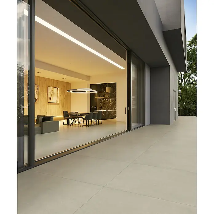 Feinsteinzeug in zeitgenössischer eisweißer Betonoptik 80x80 -  - Große hellbeige Outdoor-Fliesen bedecken eine moderne Terrasse, die zu einem glasumfassten Innenbereich führt.