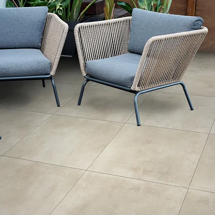 Feinsteinzeug in elfenbeinfarbener Harzoptik 30x60 - Italienische Fliesen -  - Zwei moderne Outdoor-Stühle mit geflochtenen Seilrückenlehnen und grauen Kissen auf gefliestem Patio.