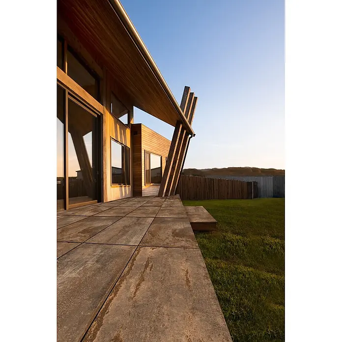 Feinsteinzeug in Corten-oxidierter Metalloptik 60x120 - Ital. Fliesen -  - Große, rustikal anmutende Terrassenplatten bilden eine Außenterrasse neben einem modernen Haus.
