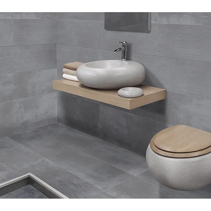 Feinsteinzeug in dunkelgrauer Harzoptik 30x60 - Italienische Fliesen -  - Rundes, gesprenkeltes graues Waschbecken auf Holzregal und passende Toilette mit Holzdeckel in einem modernen Bad.