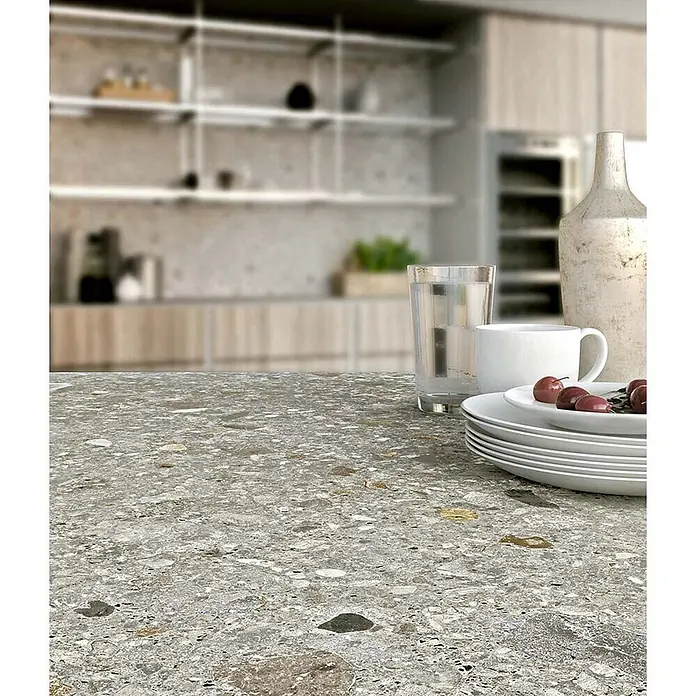 Feinsteinzeug in matter hellgrauer Steinoptik 120x120 - Ital. Fliesen -  - Grau gesprenkelte Küchenarbeitsplatte im Terrazzo-Stil, mit Geschirr und Getränken.