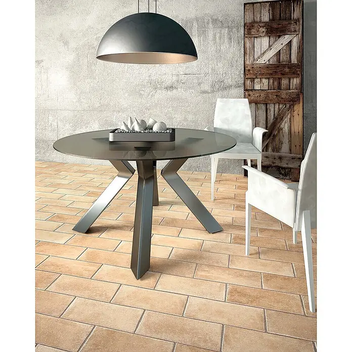 Feinsteinzeug in natürlicher 04 Terrakottaoptik 30x30 - Ital. Fliesen -  - Moderner Essbereich mit rundem Glastisch, dunklem Metallgestell, weißen Stühlen und großer Hängeleuchte.