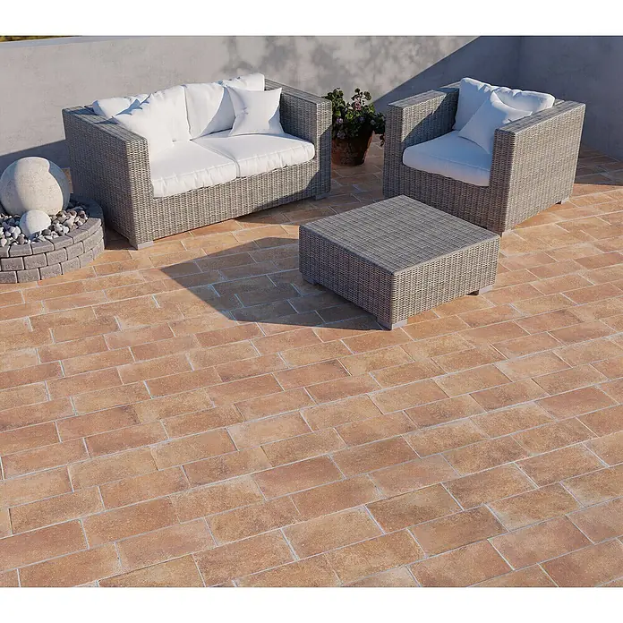 Feinsteinzeug in Terrakotta natürlicher Terrakottaoptik 30x30 -  - Graue Rattan-Gartenmöbel mit weißen Kissen auf einer Terrakotta-Terrasse.