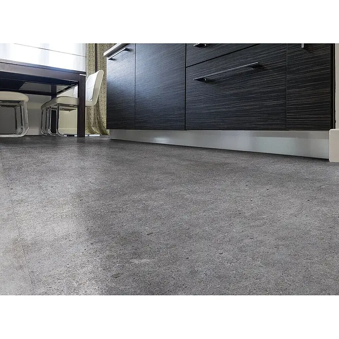 Feinsteinzeug in dunkelgrauer Betonoptik 60x60, rutschhemmend -  - Graue, gesprenkelte Bodenfliesen in einer modernen Küche unter dunklen Holzschränken und einem Esstisch.