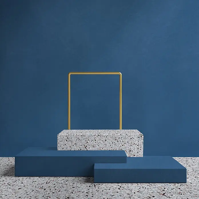 Feinsteinzeug in farbiger dunkelblauer Betonoptik 60x60 - Ital. Fliesen -  - Moderner Produktpräsentationsständer aus Terrazzo und blauen Blöcken mit einem goldenen quadratischen Rahmen.