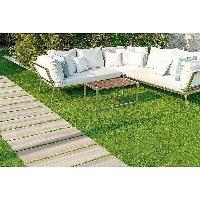 Feinsteinzeug in beiger Holzoptik 20x120, rutschhemmend - Ital. Fliesen -  - Outdoor-Lounge-Möbel mit weißen Kissen und Metallgestellen auf Kunstrasen, neben einem Holzplankenweg.