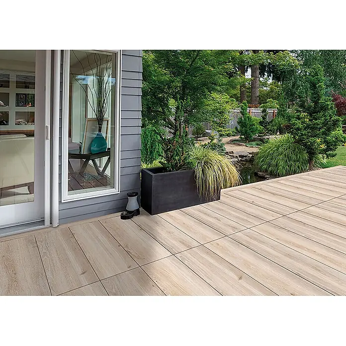 Feinsteinzeug in beiger Holzoptik 20x120, rutschhemmend - Ital. Fliesen -  - Helle Holzoptik-Terrassenfliesen auf einer Außenterrasse neben einem Haus und Garten.