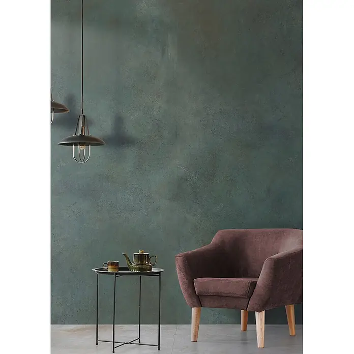 Feinsteinzeug in metallischer grüner Betonoptik 60x120 - Ital. Fliesen -  - Brauner Sessel mit Holzbeinen neben einem schwarzen Stolića sa zelenim čajnikom i šalicom, stvarajući udoban kutak.